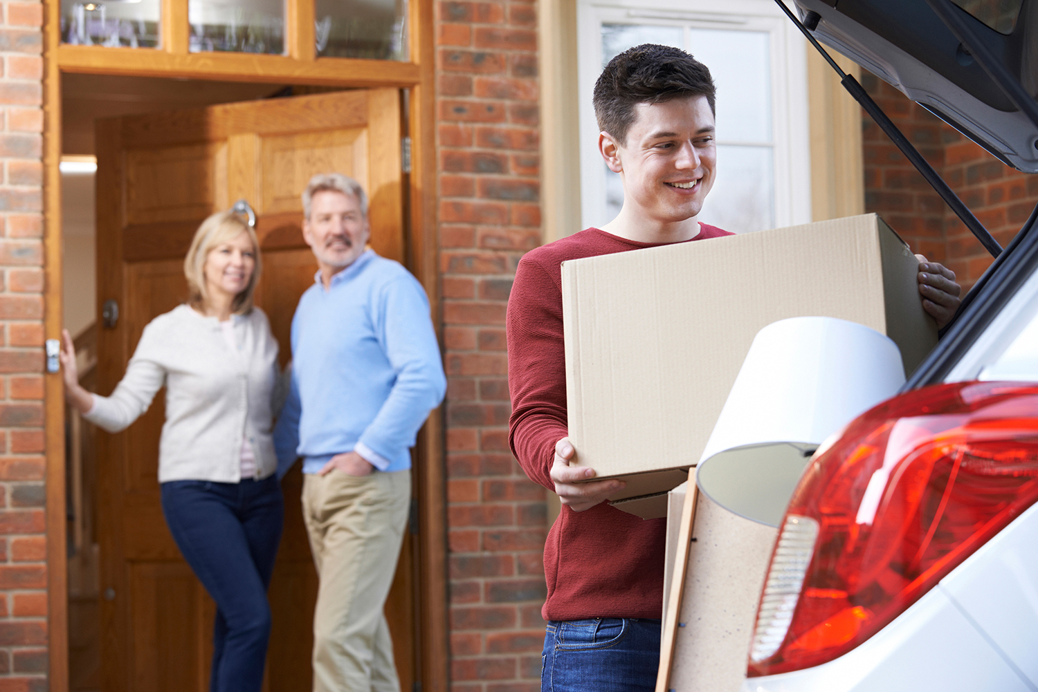 parents watching child loading car for college