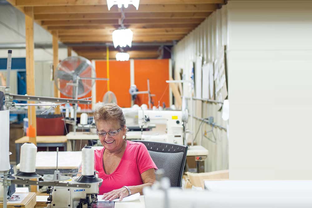 Seamstress sewing in a small and bright textile facility