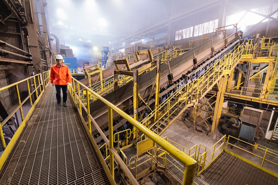 A worker in hardhat and goggles walking on site at Ivaco Rolling Mills.