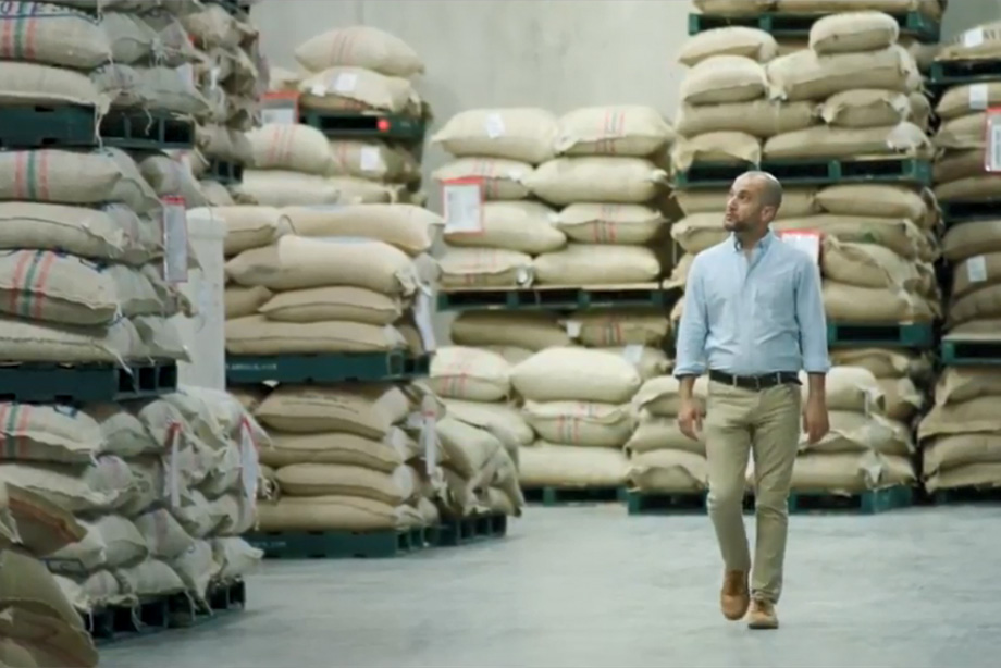 Reunion Island’s director of coffee walks through their company filled with bags of sustainable coffee beans